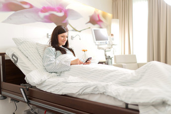 Patientin liegt im Bett eines AGAPLESION Komfortzimmers